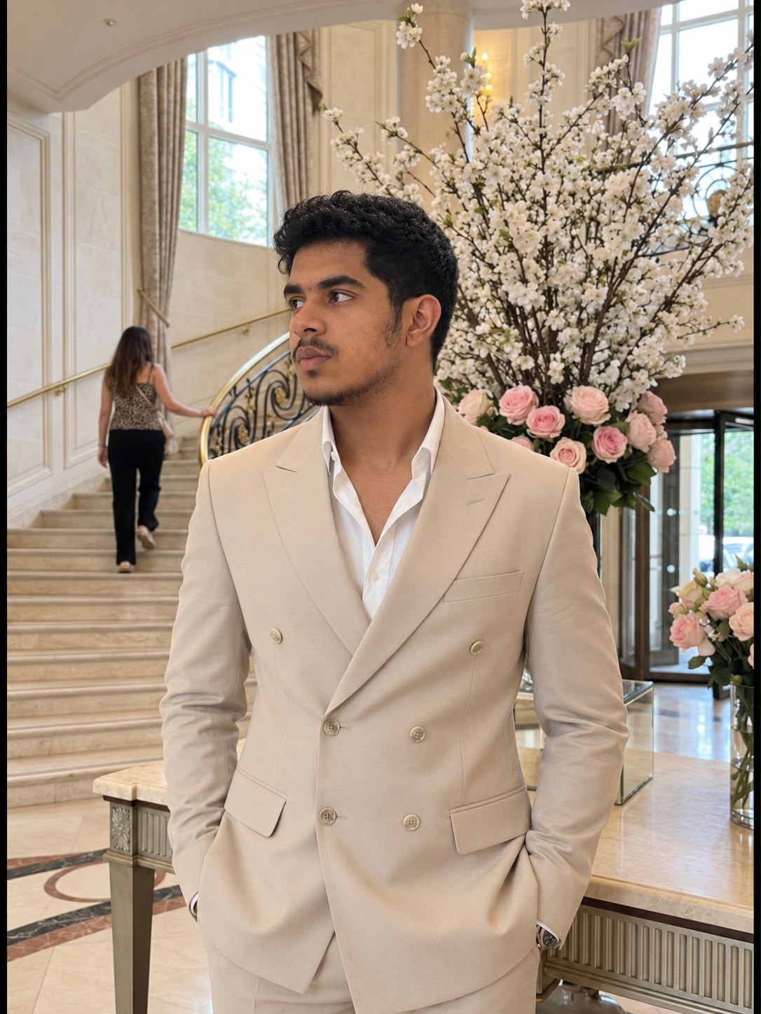 Omar Imran in a cream suit beside a staircase